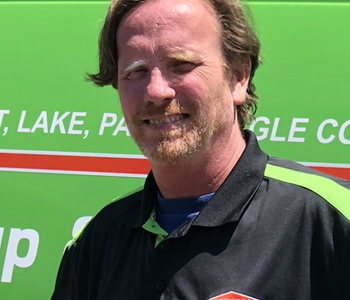 male employee posing in front of a green van.
